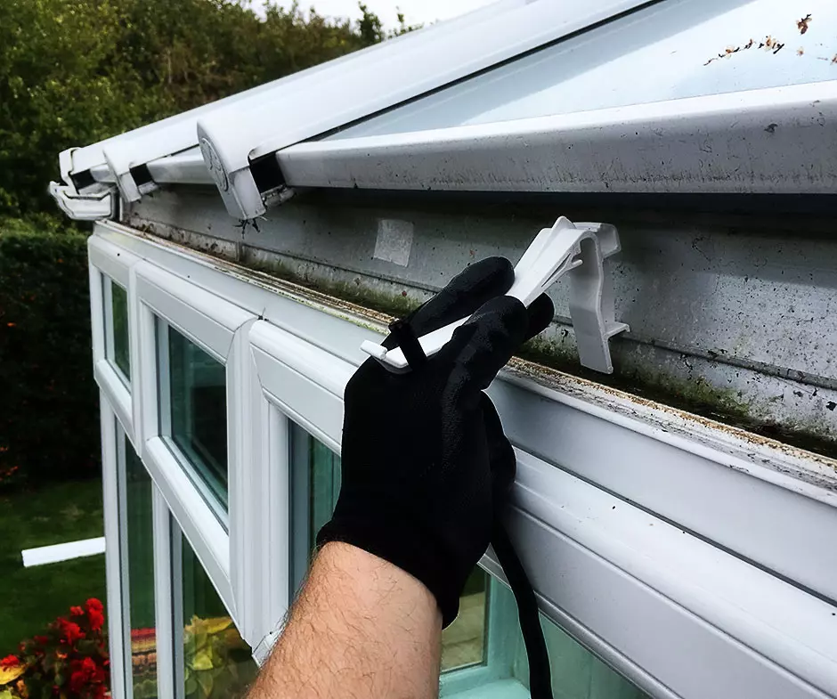 Conservatory gutter clips being replaced on a white UPVC conservatory