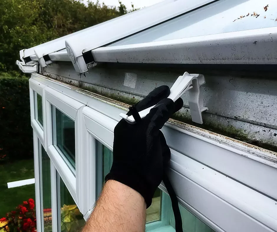 Conservatory gutter clips being replaced on a white UPVC conservatory
