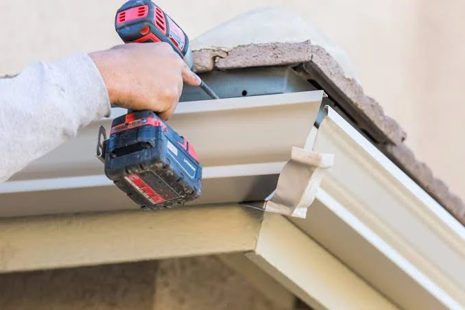 Gutter repair being secured to the roofline of a property
